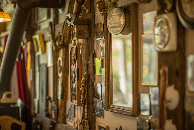 Wand voller alter Spiegel, Bilderrahmen und Fundstücke im Café